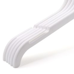 Closeup group photo of 5 white plastic clothes hangers with notches